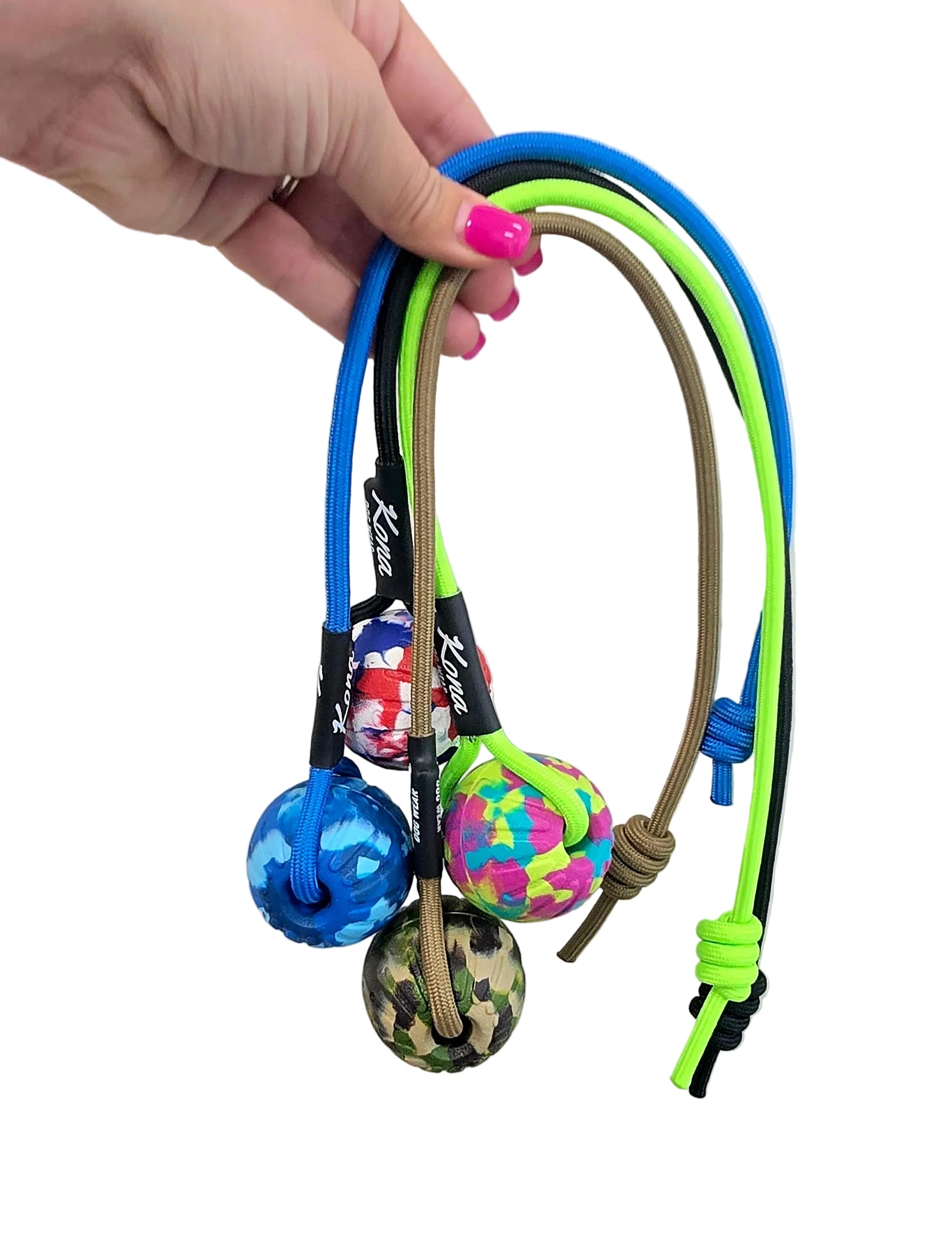 Colorful dog toy with balls and handles held by a hand against a plain background